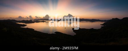 L'alba illumina il cielo sulle acque calme delle Isole Salomone. Questa regione panoramica è conosciuta per la sua spettacolare biodiversità marina. Foto Stock