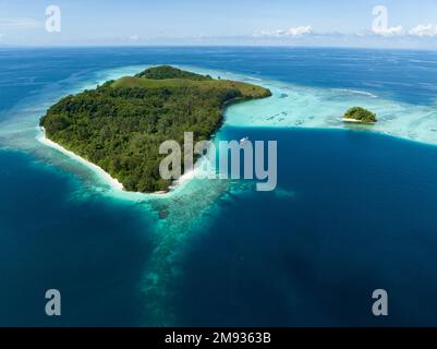 Una barca da immersione siede all'ancora accanto a un'isola remota e idilliaca nelle Isole Salomone. Questa splendida area ospita straordinarie barriere coralline. Foto Stock
