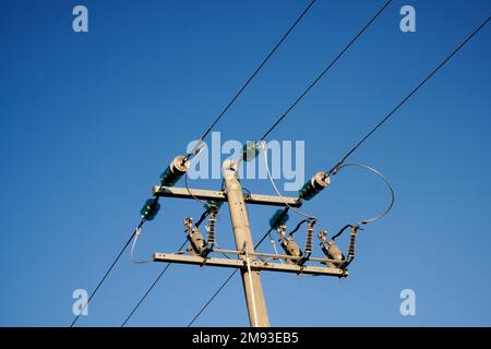 Guardando in alto il palo di potenza in cemento e le linee elettriche contro il cielo blu chiaro, Victoria, Ausralia. Foto Stock