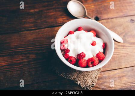 Ciotola di Dessert estivo con lamponi freschi e yogurt greco su superficie di legno Foto Stock