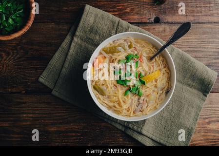 Ciotola di zuppa di Noodle con verdure e carne di anatra su tavola di legno. Vista dall'alto Foto Stock