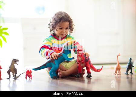 Bambino che gioca con dinosauri colorati giocattolo. Giocattoli educativi per bambini. Ragazzino imparando fossili e rettili. I bambini giocano con i giocattoli dei dinosauri. Foto Stock