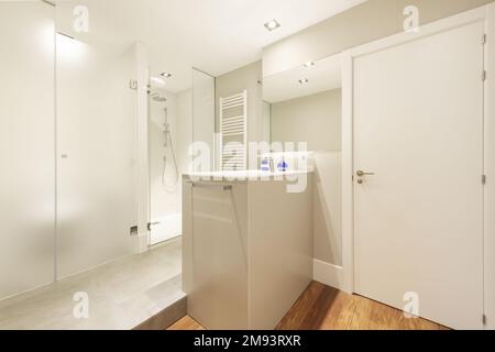 Bagno di design con lavabo centrale in marmo e doccia e wc separati con divisori in vetro temperato Foto Stock