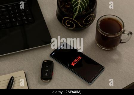 Messico, CDMX - 01 maggio 2022: Telefono cellulare con il logo netflix sullo schermo, su una scrivania con un computer portatile, il caffè e le chiavi dell'auto. Foto Stock