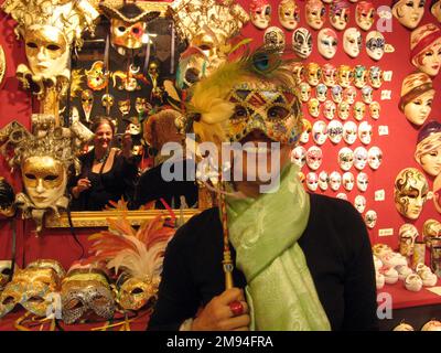 Maschere e riflessi in un negozio di maschere veneziane. Foto Stock