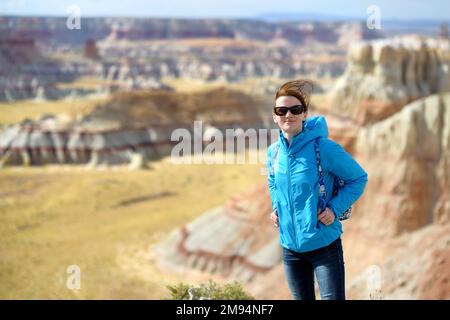 Giovane escursionista femminile ammirando le vedute delle splendide formazioni di arenaria a strisce del Coal Mine Canyon, Arizona, USA. Esplorando il sudovest americano. Foto Stock