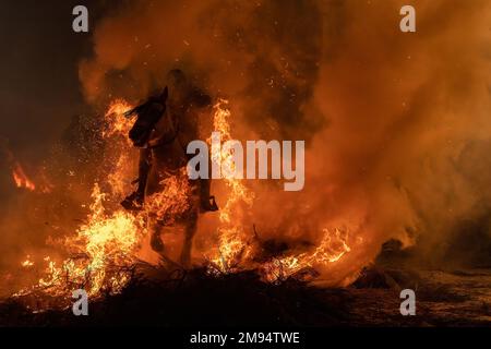 San Bartolome De Pinares, Spagna. 16th Jan, 2023. Un cavaliere attraversa un falò fatto con rami di pino nel villaggio di San Bartolome de Pinares durante la tradizionale festa religiosa di 'Las Luminarias' in onore di San Antonio Abad (Sant'Antonio), santo patrono degli animali celebrato ogni notte del 16 gennaio. I cavalieri partecipano ad una processione con i loro cavalli e asini, attraversando i molteplici falò illuminati sulle strade della Città. (Foto di Guillermo Gutierrez/SOPA Images/Sipa USA) Credit: Sipa USA/Alamy Live News Foto Stock