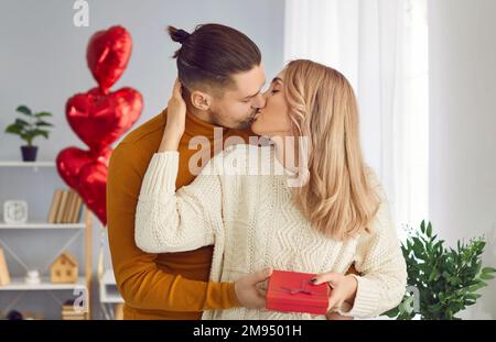 Bella, giovane coppia a casa in un'atmosfera romantica si congratulano l'una con l'altra il giorno di San Valentino e dare regali. Foto Stock