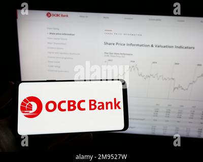 Persona che tiene il telefono cellulare con il logo di Oversea-Chinese Banking Corporation (OCBC Bank) sullo schermo di fronte alla pagina web. Messa a fuoco sul display del telefono. Foto Stock