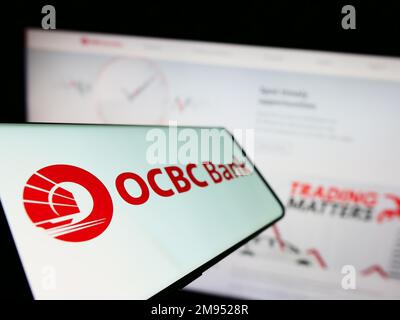 Smartphone con il logo della società Oversea-Chinese Banking Corporation (OCBC Bank) sullo schermo di fronte al sito Web. Messa a fuoco a sinistra del display del telefono. Foto Stock