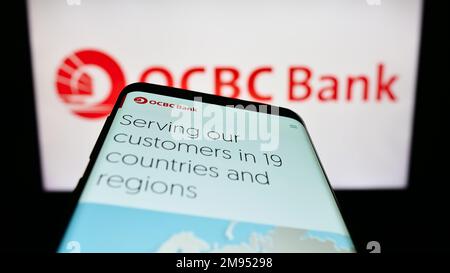 Telefono cellulare con pagina web di Oversea-Chinese Banking Corporation (OCBC Bank) sullo schermo di fronte al logo. Messa a fuoco in alto a sinistra del display del telefono. Foto Stock