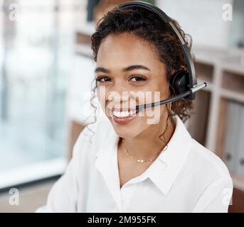 Im sicuro che posso aiutare. Ritratto ritagliato di una giovane e attraente agente di call center che lavora alla sua scrivania in ufficio. Foto Stock