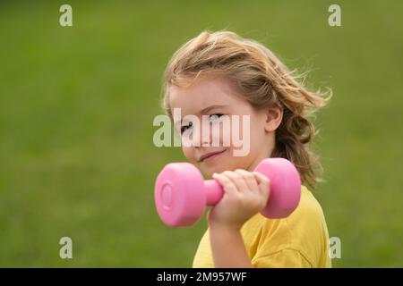 Esercizi sportivi per bambini. Vita sana dei bambini e concetto di sport. Ritratto del bambino che lavora fuori con i manubri. Motivazione e concetto di sport per Foto Stock