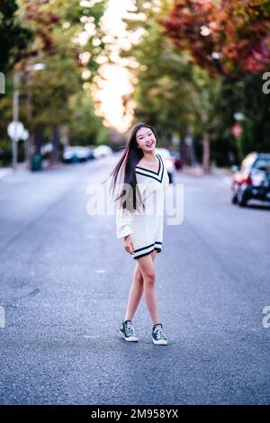 Bella ragazza Teenage in piedi su Suburban Street al tramonto Foto Stock