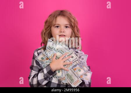 Capretto che mostra le fatture del dollaro dei soldi, sognando levante in piedi dei ricchi contro lo sfondo rosso isolato dello studio rosa. Foto Stock