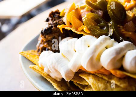 Nachos con guacamole. I nachos sono un piatto di origine messicana, che consiste nella frittura di tortilla di mais ricoperta di un formaggio speciale. Foto Stock