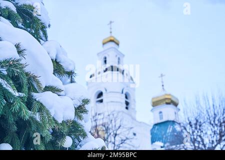 Sfondo di Natale. La parte superiore dorata della chiesa cristiana ortodossa sullo sfondo del cielo blu e dei rami di abete innevati. Spazio per la copia. Foto di alta qualità Foto Stock