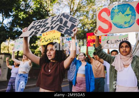 Gruppo di adolescenti che si oppongono al cambiamento climatico e al riscaldamento globale. Attivisti giovanili multiculturali che protestano con manifesti e striscioni. Diverso t Foto Stock