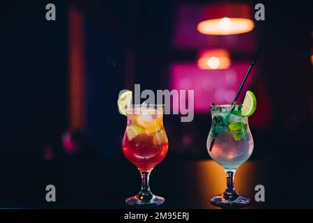 due bicchieri con cocktail di frutta con lime, arancia e menta e cannucce alla festa al bar Foto Stock
