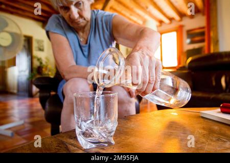 Anziani e ondata di calore: Rimanere idratati. Calore intenso: Vecchia donna che beve acqua. Illustrazione, persone anziane e idratazione, rischio di disidratazione Foto Stock