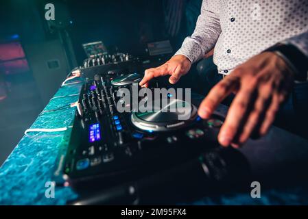 DJ suona la musica al night club della festa controllando i pulsanti e i livelli Foto Stock