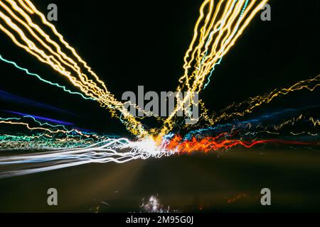 tracce sfocate di colore chiaro da auto e luci sulla strada di notte con uno sfondo scuro Foto Stock