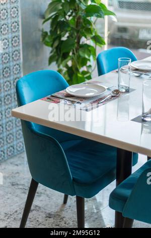 Un colpo verticale di sedie blu e posate sul tavolo del ristorante. Foto Stock