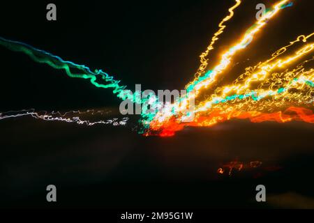 sfondo scuro con tracce sfocate dalle luci delle auto sulla strada attraverso il vetro a velocità Foto Stock