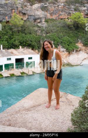 Donna in piedi su una sporgenza sopra il mare in bella luce solare morbida, Cala Pi Foto Stock