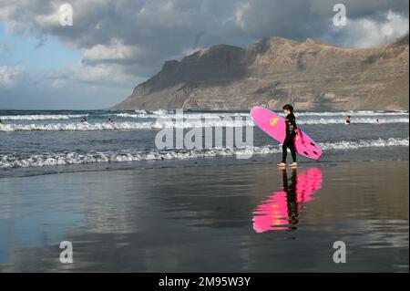 Surfers sulla spiaggia di Caleta de Famara, Playa de Famara, Lanzarote. Foto Stock
