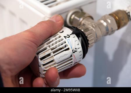 La mano maschio fa ruotare un termostato del radiatore Foto Stock