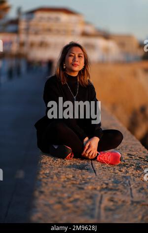 Spedizione giovane donna seduta sul molo al tramonto. Foto Stock