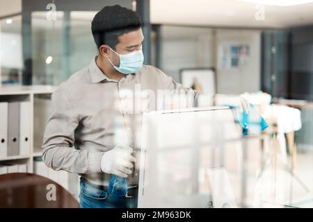Mantenere uno spazio di lavoro pulito. un uomo d'affari che pulisce il suo computer con l'igienizzatore in ufficio. Foto Stock