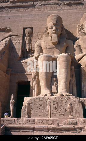 Primo piano di una delle quattro statue sedute di RAMESES II ('il Grande'), con una statua più piccola della dea Re- Harachte (a sinistra), Tempio di Rameses II - Abu Simbel Egitto Foto Stock