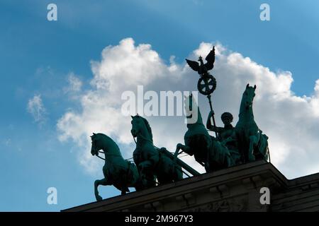La Quadriga (quattro cavalli che disegnano un carro), vista qui in una silhouette contro il cielo, sulla porta di Brandeburgo a Berlino, in Germania. Foto Stock