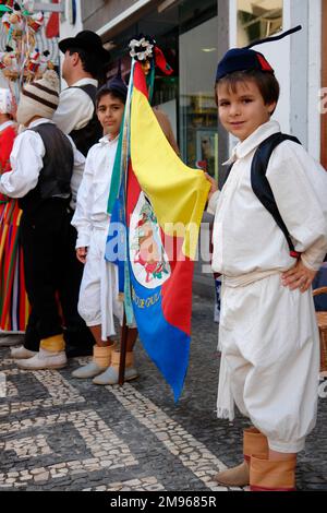 Due ragazzi appartenenti ad un gruppo folcloristico di Gaula che sorreggono una bandiera in una strada a Funchal, la capitale di Madeira. Foto Stock