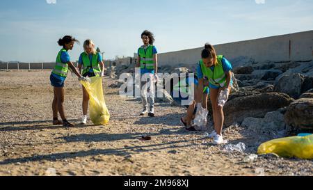 Persone che puliscono la spiaggia, volontari che raccolgono i rifiuti sulla linea costiera, giovani studenti che lavorano in team consapevoli dell'inquinamento prodotto dal Foto Stock