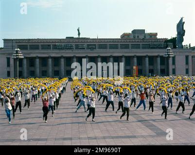 Giovani in formazione in Piazza Kim il Sung, di fronte al Museo di Storia Centrale Coreano, Pyongyang, capitale della Corea del Nord. Si allenano per uno spettacolo di massa che si svolge in uno stadio sportivo. Foto Stock