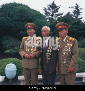 Tre veterani della guerra di Corea (1950-1953) posano per la loro foto a Pyongyang, capitale della Corea del Nord. Due sono nelle loro uniformi, uno è in un vestito, e tutti e tre indossano molte medaglie e decorazioni. Foto Stock