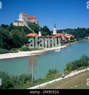 Vista del castello gotico sul fiume Salzach nella città di Burghausen, nella Baviera sud-orientale, Germania. Il castello, in cima ad un crinale, è il più lungo complesso di castelli d'Europa. Si può vedere anche la chiesa parrocchiale di San Jakob, con una cupola sulla guglia, più in basso verso il fiume. Foto Stock