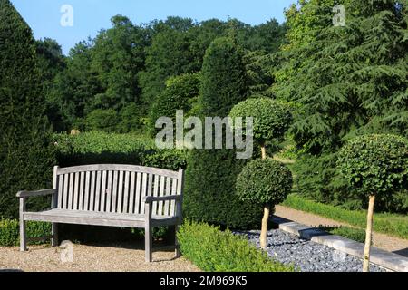 Panca in legno in un giardino paesaggistico. Saint-Sauveur-en-Puisaye. Yonne. Borgogna. Francia. Europa. Foto Stock