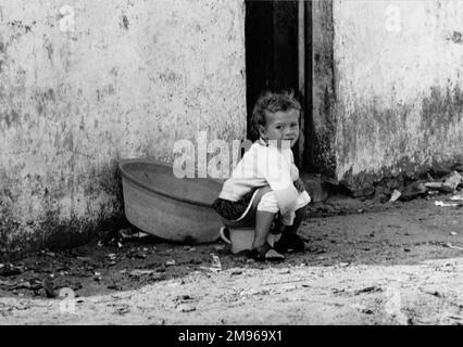 Una bambina, forse una zingara, seduta su un vasino per strada! Foto Stock