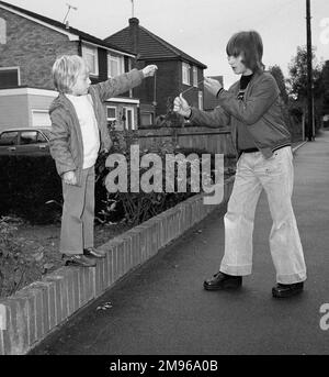 Due ragazzi che giocano a Conkers in una strada suburbana. Foto Stock