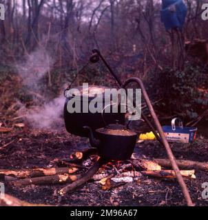 Un calderone e un bollitore che si riscaldano sopra un fuoco di legna all'aria aperta ad un accampamento zingaro. Foto Stock