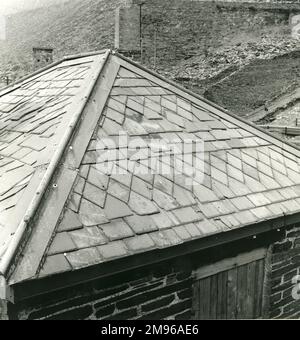 Intricati motivi in ardesia sul tetto di un edificio abbandonato a ponte pesante a Blaenau Ffestiniog Slate Quarry, Caernarvonshire (ora Gwynedd), Galles del Nord. La struttura dell'edificio è anche di ardesia di rifiuti, così come molti altri edifici della zona, comprese le case. Foto Stock