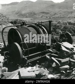 Una manovella a vapore 'Blondin', abbandonata sopra Penyrorsedd Slate Quarry, Nantlle Valley, Caernarvonshire (ora Gwynedd), Galles del Nord. C'è un mucchio di ardesia rotta davanti ad esso. Foto Stock