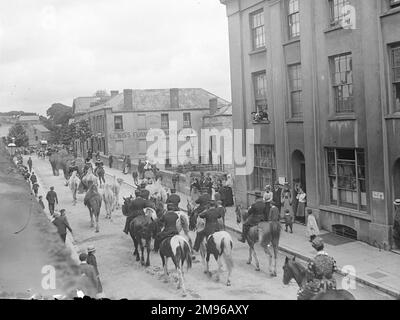 Il circo parata lungo il Ponte nuovo a Haverfordwest, Pembrokeshire, Dyfed, Galles del Sud, con elefanti, cammelli e cavalli. I cittadini si fermano e guardano, e alcuni seguono la sfilata lungo il marciapiede. Il magazzino dell'arredamento di Lewis può essere visto sullo sfondo. Foto Stock