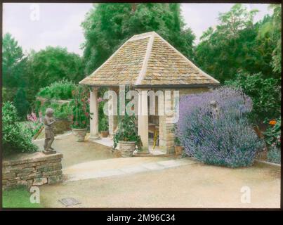 Un posto a sedere in giardino nei giardini formali di Abbotswood, Stow on the Wold, Gloucestershire. Il sedile è dotato di due pilastri in stile classico (toscano) nella parte anteriore e di un tetto piastrellato. I giardini sono stati creati da Sir Edwin Lutyens. Foto Stock