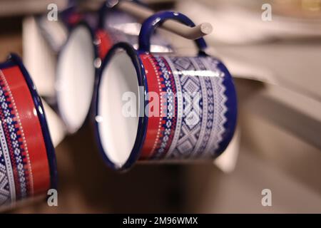 Un fuoco selettivo delle tazze smaltate colorate appese ai supporti Foto Stock