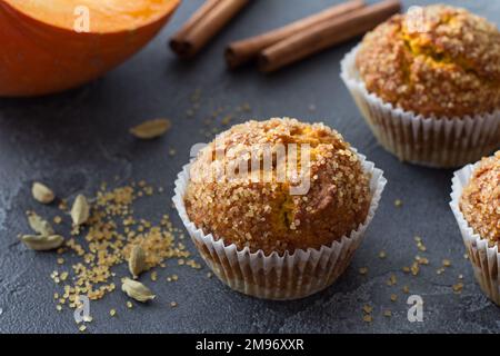 Deliziosi muffin fatti in casa alla zucca con crosta di zucchero piccante con latte su fondo testurizzato nero, spazio Foto Stock